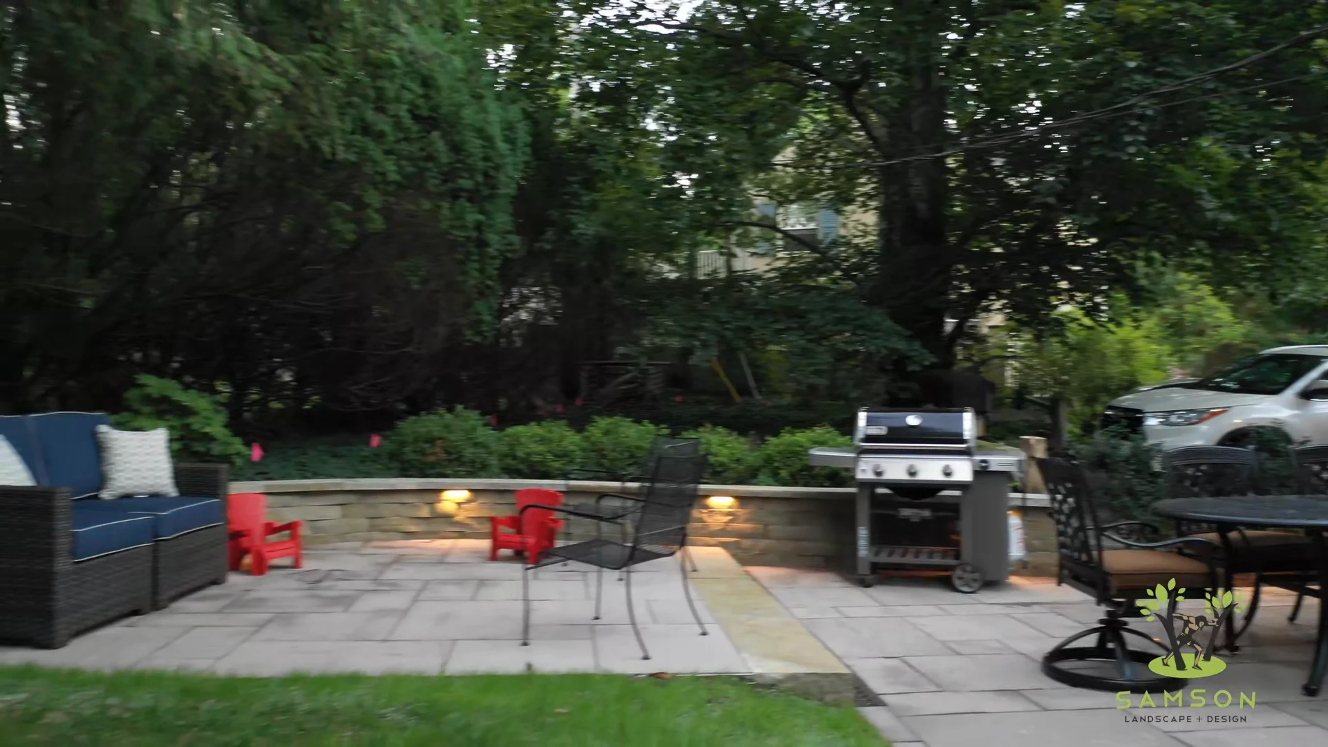 Finished patio at dusk with a lit seat wall, seating and grill